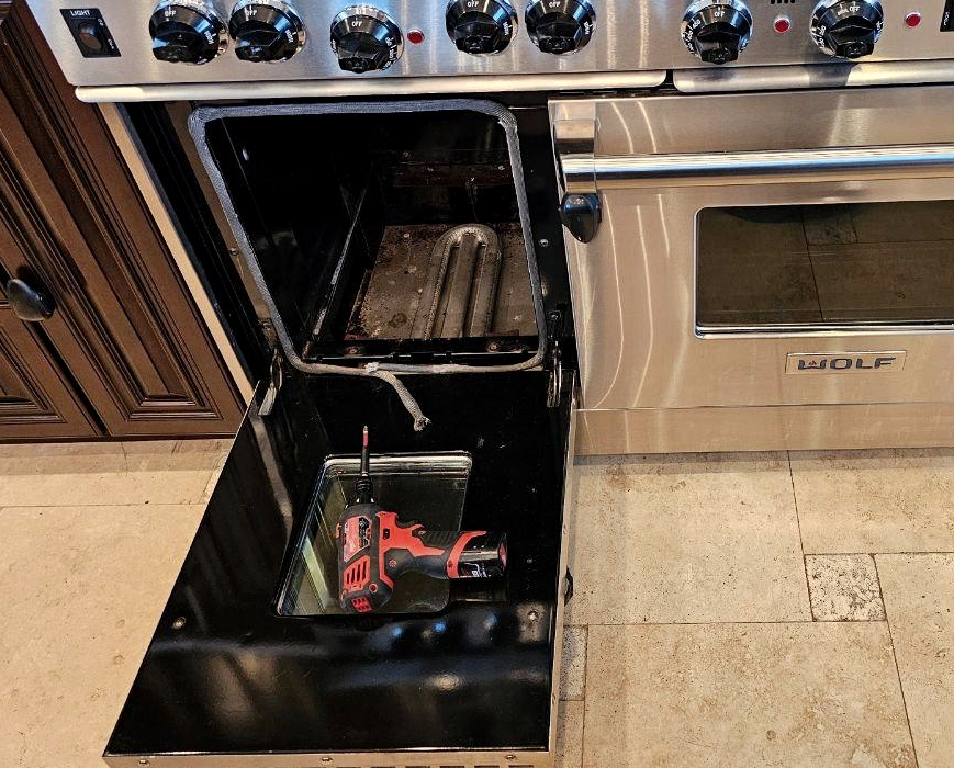 Wolf dual fuel range with left oven opened during lower heating element replacement and internal repair